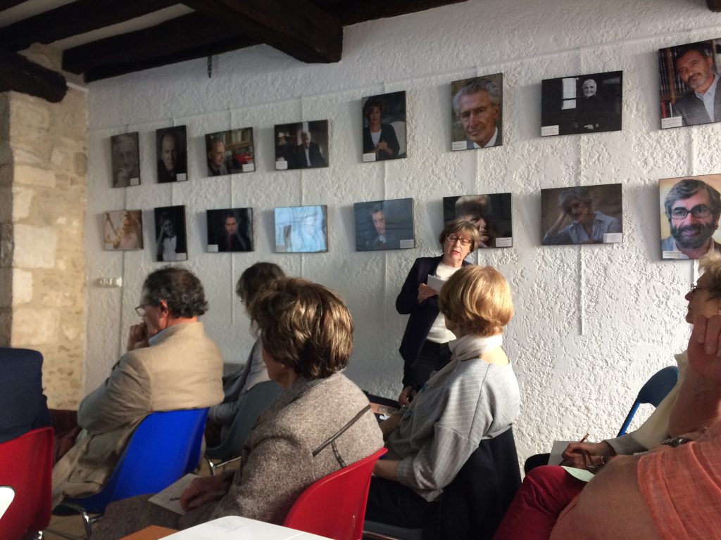 Françoise Dion, alors vice-présidente de LEC, lit un extrait de roman aux personnes assises devant une exposition de photos d'ancien-ne-s invité-e-s.